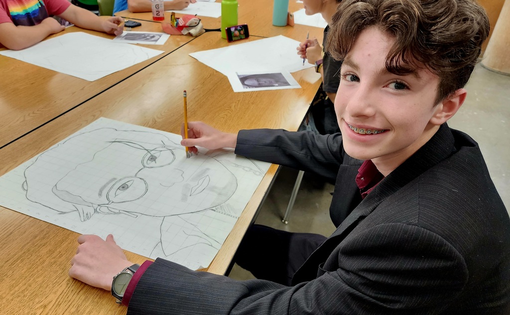a male student drawing with a pencil